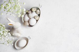 Monochrome white Easter card or invitation. Natural color eggs, ceramic bunny, Gypsophila flowers. photo