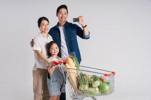 Image of Asian family pushing a supermarket cart while shopping, isolated on white background photo