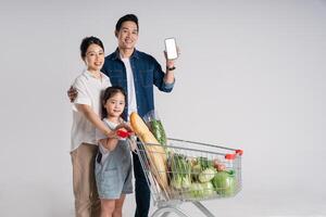 Image of Asian family pushing a supermarket cart while shopping, isolated on white background photo