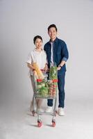 Image of Asian couple pushing supermarket cart while shopping, isolated on white background photo