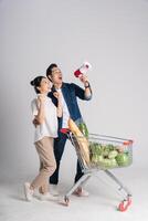 Image of Asian couple pushing supermarket cart while shopping, isolated on white background photo