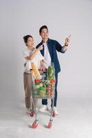 Image of Asian couple pushing supermarket cart while shopping, isolated on white background photo