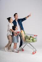 Image of Asian family pushing a supermarket cart while shopping, isolated on white background photo
