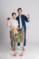 Image of Asian couple pushing supermarket cart while shopping, isolated on white background photo