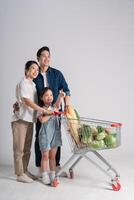 Image of Asian family pushing a supermarket cart while shopping, isolated on white background photo