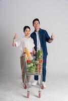 Image of Asian couple pushing supermarket cart while shopping, isolated on white background photo