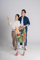 Image of Asian couple pushing supermarket cart while shopping, isolated on white background photo