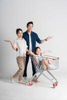 Image of Asian family pushing a supermarket cart while shopping, isolated on white background photo