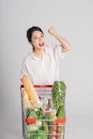 Smiling woman happily pushing a supermarket cart, isolated on white background photo