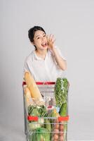 Smiling woman happily pushing a supermarket cart, isolated on white background photo