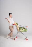 Smiling woman happily pushing a supermarket cart, isolated on white background photo