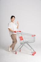 Smiling woman happily pushing a supermarket cart, isolated on white background photo