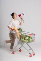 Smiling woman happily pushing a supermarket cart, isolated on white background photo