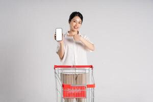 Smiling woman happily pushing a supermarket cart, isolated on white background photo