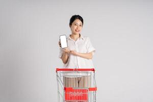 Smiling woman happily pushing a supermarket cart, isolated on white background photo