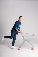 Happy smiling man pushing supermarket cart isolated on white background photo