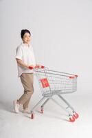 Smiling woman happily pushing a supermarket cart, isolated on white background photo