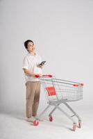 Smiling woman happily pushing a supermarket cart, isolated on white background photo