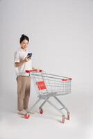 Smiling woman happily pushing a supermarket cart, isolated on white background photo