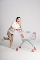 Smiling woman happily pushing a supermarket cart, isolated on white background photo