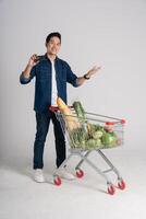 Happy smiling man pushing supermarket cart isolated on white background photo