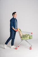 Happy smiling man pushing supermarket cart isolated on white background photo