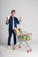 Happy smiling man pushing supermarket cart isolated on white background photo