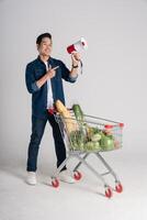 Happy smiling man pushing supermarket cart isolated on white background photo