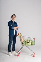 Happy smiling man pushing supermarket cart isolated on white background photo