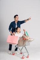 Happy smiling couple pushing supermarket cart isolated on white background photo