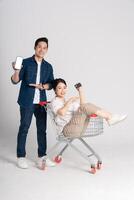 Happy smiling couple pushing supermarket cart isolated on white background photo