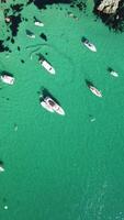 Aerial vertical view of seascape with crystal clear azure sea and rocky shores. Yachts in a beautiful lagoon on backdrop of rocks. The concept of an ideal destination for summer travel and vacation. video