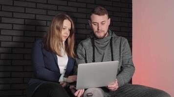 equipo colaboración con computadora portátil, un hombre y mujer revisando contenido juntos en un ordenador portátil en un moderno espacio de trabajo video