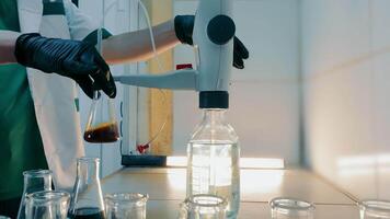 Laboratory Technician Adjusting Flask, Scientist adjusting a flask with a dark liquid under a lab apparatus. video