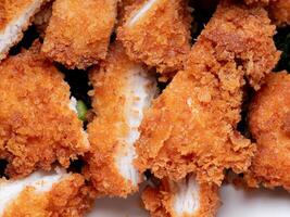 Fried Chicken Ingredients include bread crumbs. One of the most popular fried foods. Chopped or sliced fried chicken placed on a white plate. photo