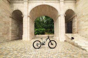 Freestanding mountain bike against the backdrop of architectural arches. MTB cover concept photo