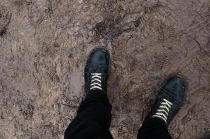 Boots standing in mud and slush, pov. Concept bad weather, off-road, thaw photo