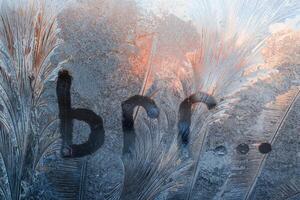 Inscription Brr on the frozen glass. Frosty patterns on window, winter background. Cold weather concept photo