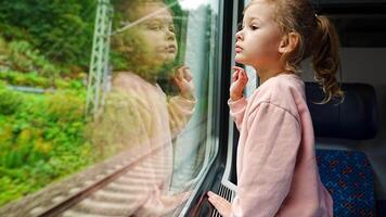 Little girl looking out train window outside, during moving. Traveling by railway in Europe. High quality 4k footage video