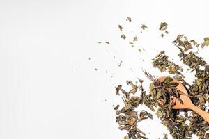 Dry fruit tea leaves in a wooden spoon. Scattered tea leaves on white background, top view copy space photo