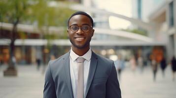 ai generado alegre sonriente joven inteligente hombre en un negocio traje y lentes en pie en ciudad centrar mirando a cámara, al aire libre foto