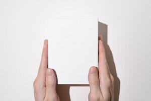 Man showing white box mock up top view. Male hands holding an empty box on a light background. photo