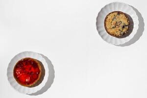 Two different cheesecakes with wild berries on a white table. Flat lay, top view, copy space. photo