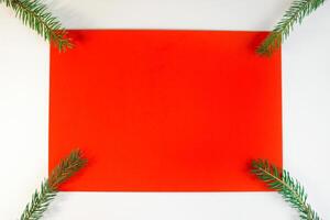 Christmas composition, flat lay. Blank red card, white frame and Christmas tree branches. Winter background top view, copy space photo