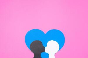 Paper silhouettes of kissing gay couple on pink background, flat lay. Interracial same-sex relationship concept photo