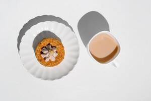 Cup of tea and cake decorated with cream and walnuts, top view. Morning breakfast with dessert in the kitchen. photo