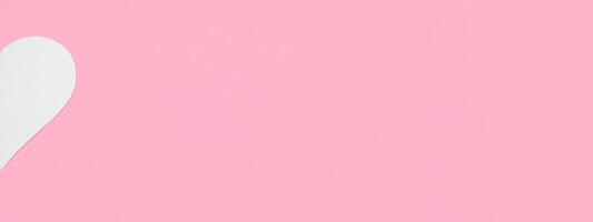 medio blanco corazón en un pastel rosado antecedentes. San Valentín día concepto. amor bandera. plano poner, parte superior vista, Copiar espacio foto