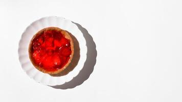 Cheesecake with strawberries in syrup on a plate, white table background. Food banner. Flat lay, top view, copy space. photo