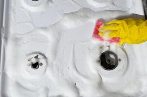 Woman cleans gas stove, top view.. Female hand in glove washing gas panel with sponge. Hygienic kitchen cleaning photo