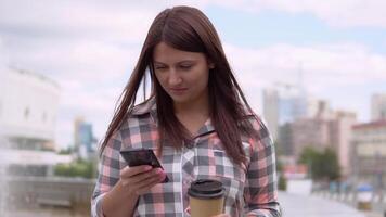 bellissimo ragazza nel un' vestito si siede vicino un' Fontana nel il parco e usi un' smartphone. lento movimento. avvicinamento video